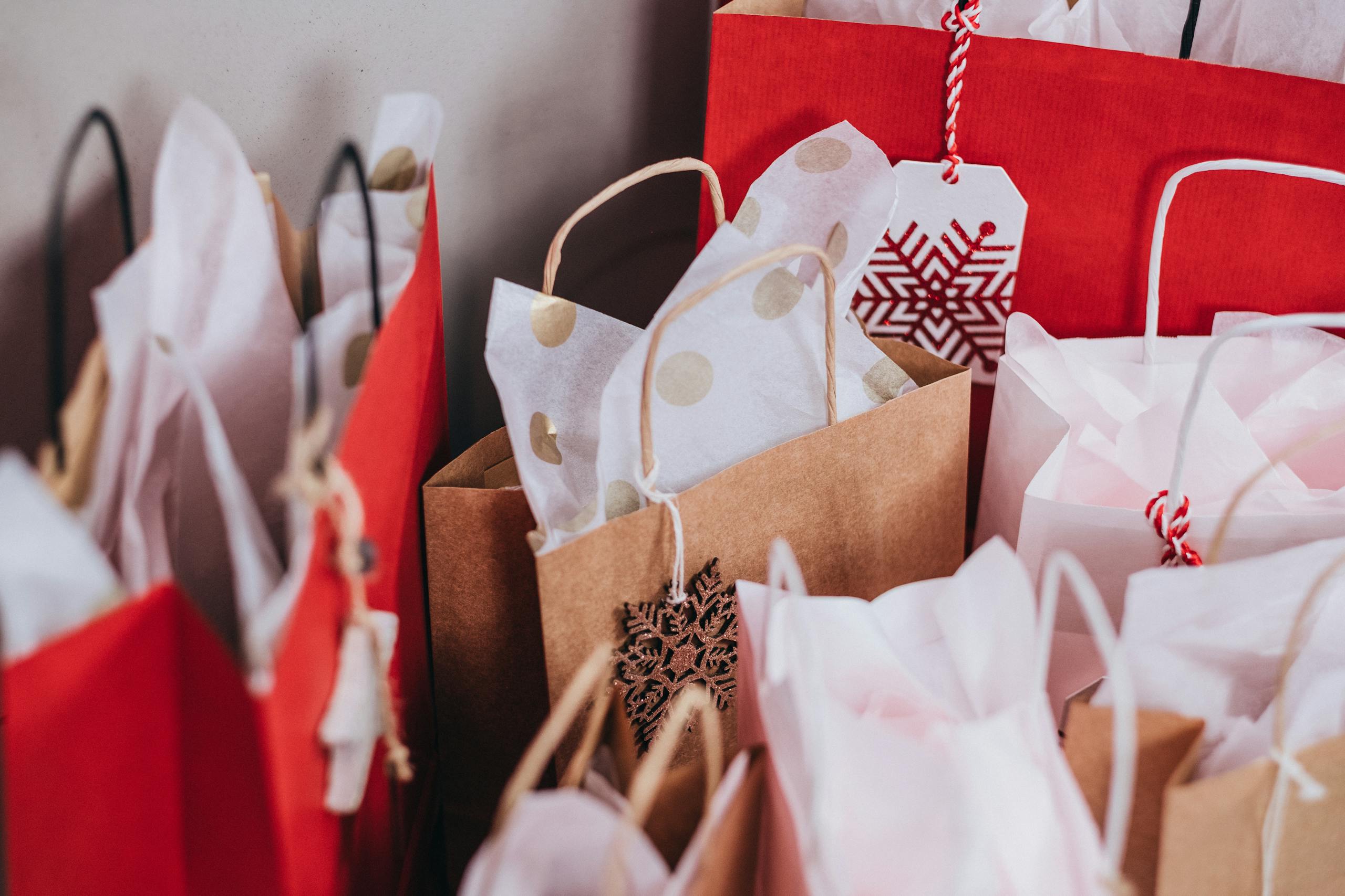 Collection of festive shopping bags filled with holiday gifts.